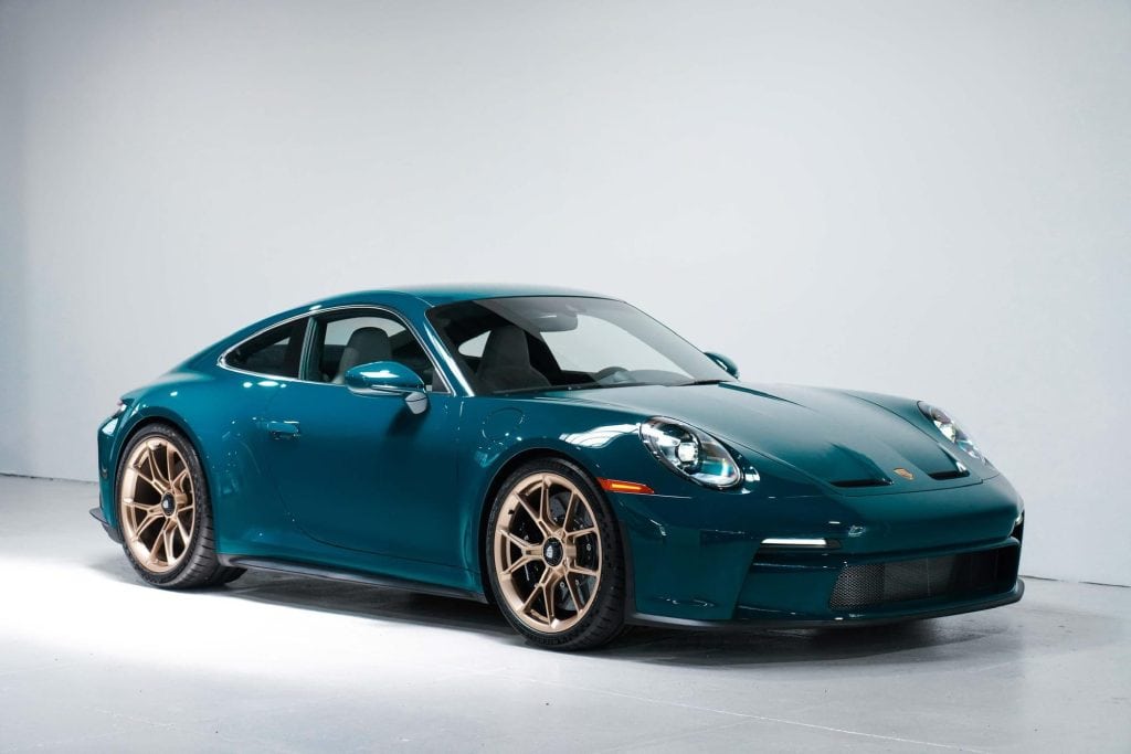 High-performance blue sports car with gold wheels in a studio setting.